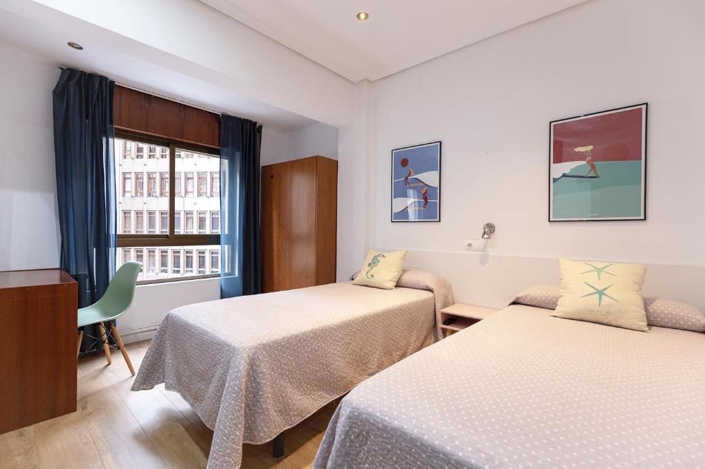 una camera d'albergo con due letti e una finestra di Pension Angelines, Sneuu Hostel Santander a Santander