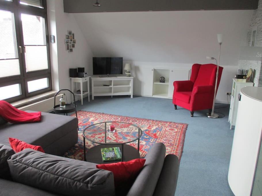 a living room with a couch and a red chair at Ferienwohnung Ganz Oben, Stadtmitte Hermeskeil in Hermeskeil