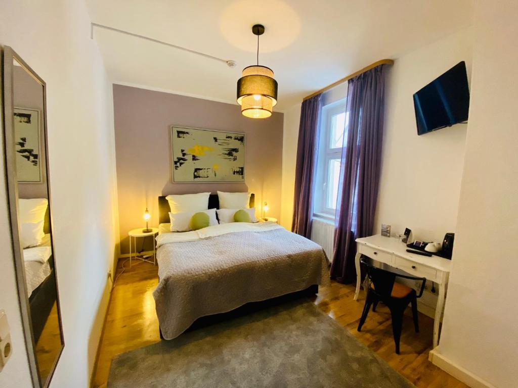 a bedroom with a bed and a desk and a window at Bärliner Hotel in Erfurt