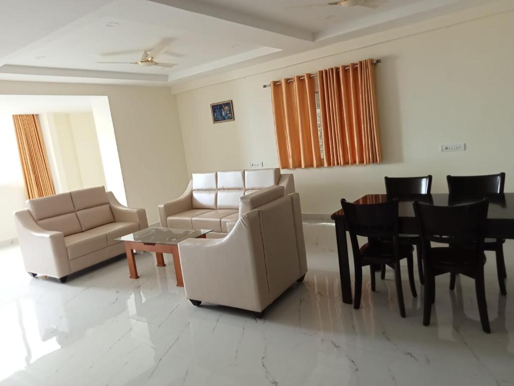 a living room with couches and a table and chairs at Sathya Sai Sankalp Hotel in Puttaparthi