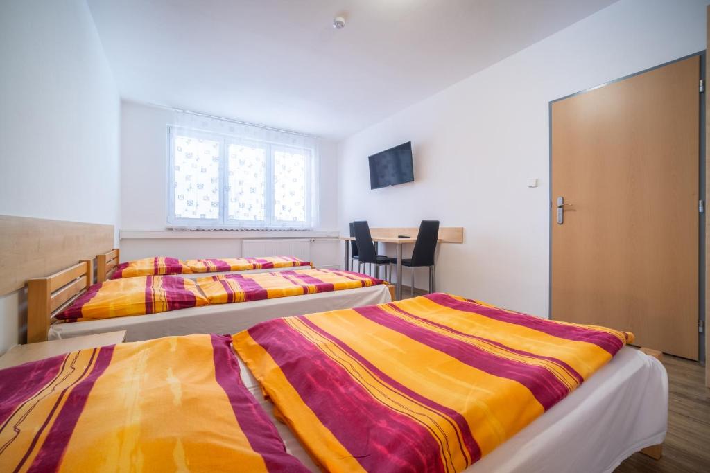 twee bedden in een kamer met een raam en een tafel bij Hotel U Nádraží in České Budějovice