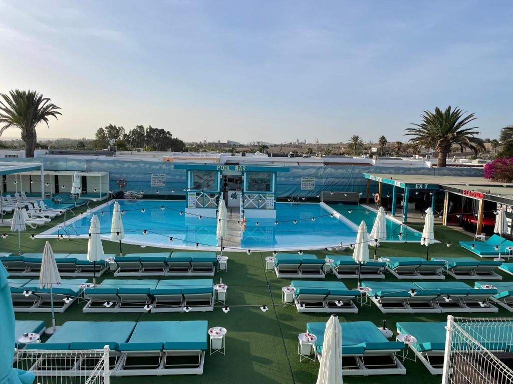 una grande piscina con sedie e ombrelloni di Venus Star Resort - FKK Nudist Swingers - Only Couples a Maspalomas