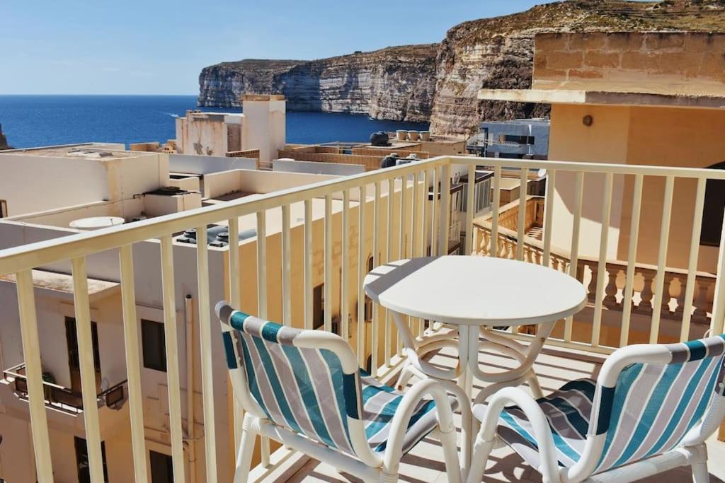 einen Tisch und Stühle auf einem Balkon mit Meerblick in der Unterkunft Seaview 2-bedroom Apartment in Xlendi in Xlendi
