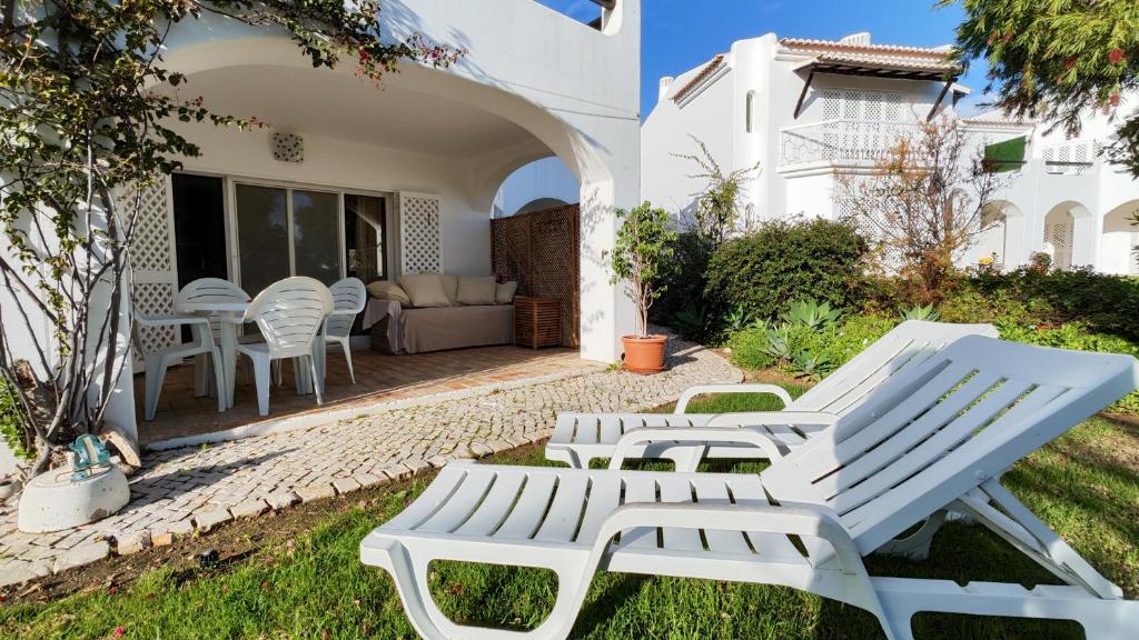 Cette maison blanche dispose d'une terrasse avec des chaises et un canapé. dans l'établissement Sao Rafel Beach house, à Albufeira