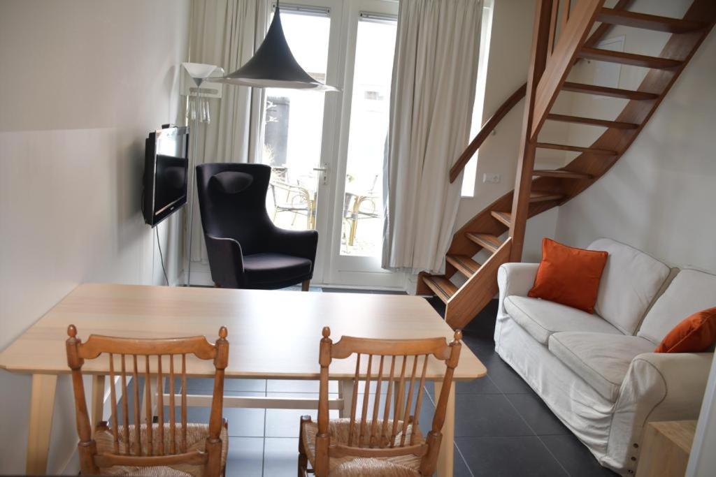 een woonkamer met een bank, een tafel en stoelen bij Hotel Steeds aan Zee in Katwijk