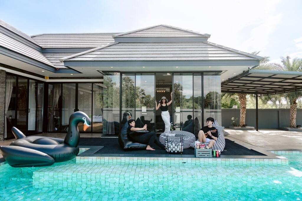 a group of people sitting around a pool in a house at Onyx Stay Pool Villa @Pranburi in Ban Nong Sua