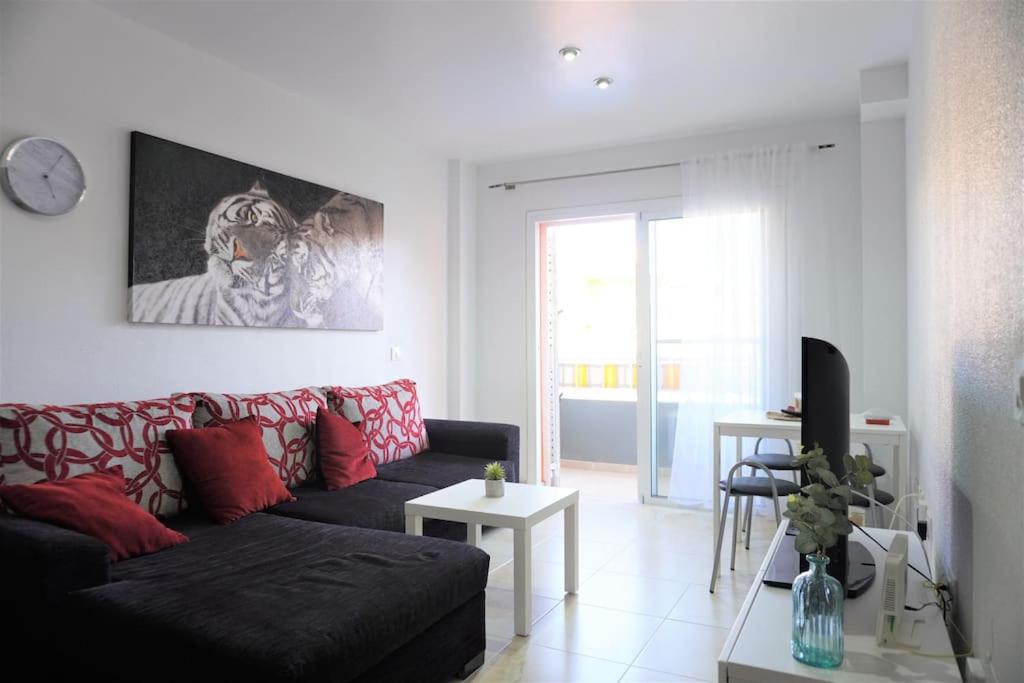 a living room with a black couch and red pillows at South Coast Apartment in Puertito de Güímar