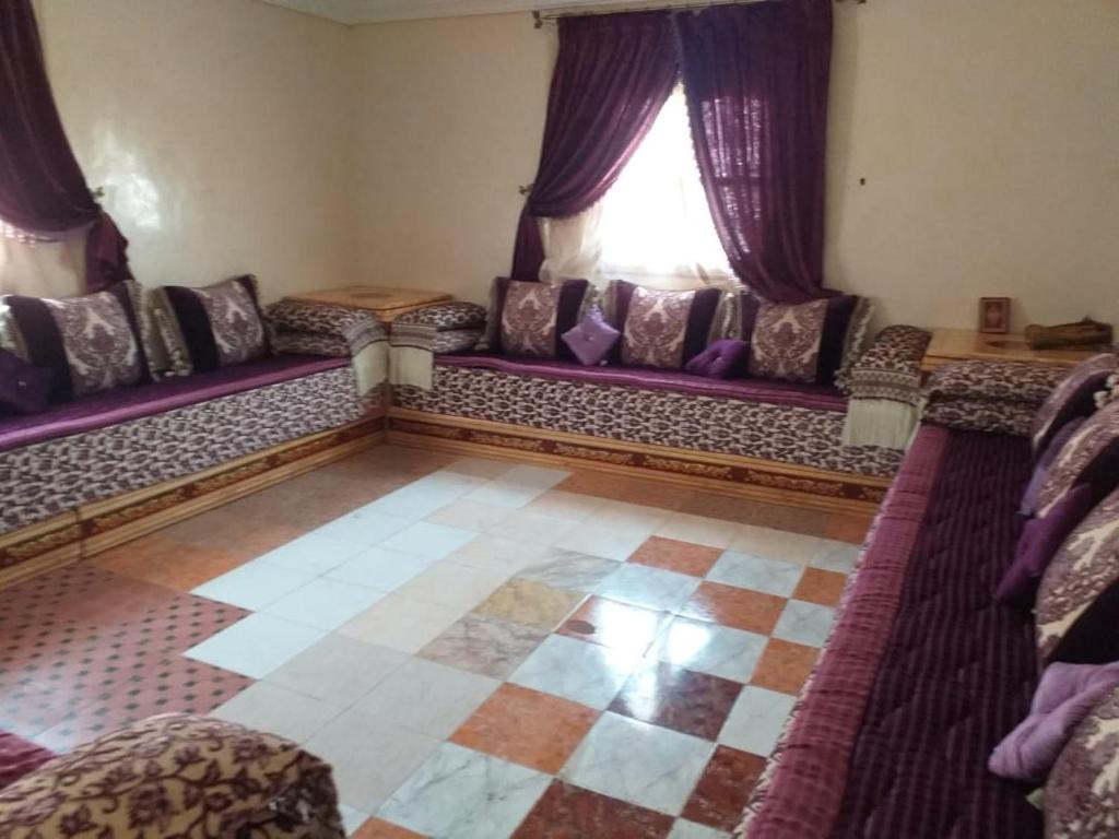 a living room with purple couches and a window at agadir hassania in Agadir