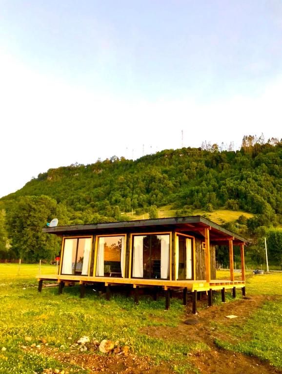a house in a field with a hill in the background at Vistaranco Eco in Lago Ranco