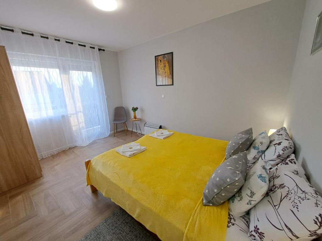 una camera da letto con un grande letto giallo con cuscini di Apartments Manna Palic a Palić
