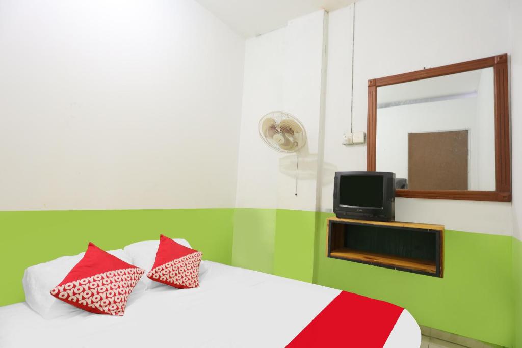 1 dormitorio con cama con almohadas rojas y espejo en SPOT ON 92053 Bagus Stay, en Tanjung Pinang