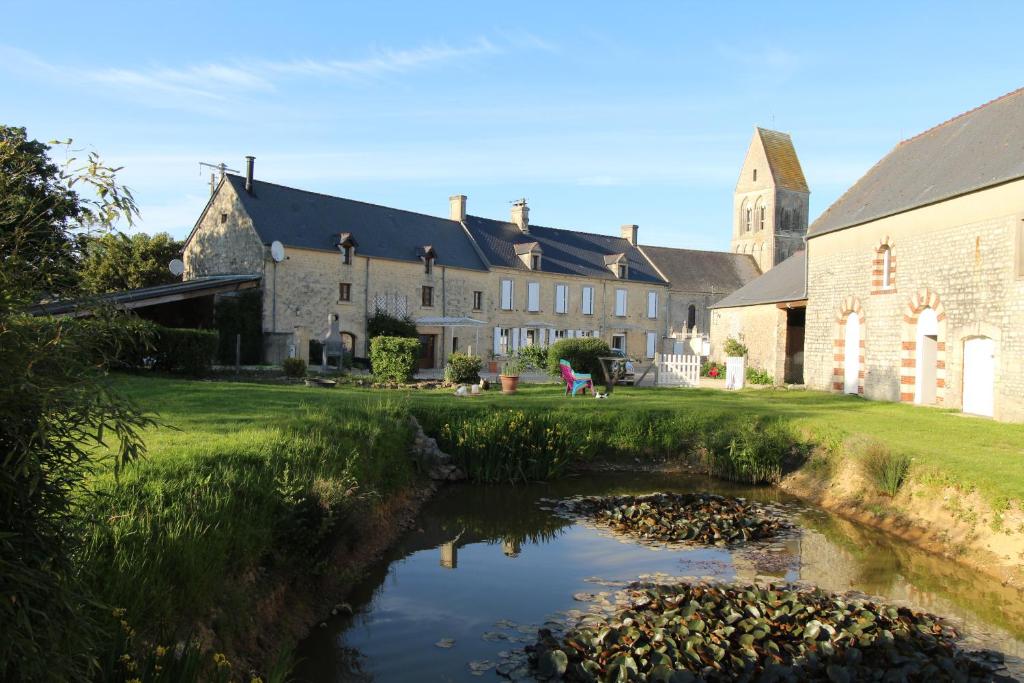 a house with a pond in front of a building at La ferme aux chats in Formigny