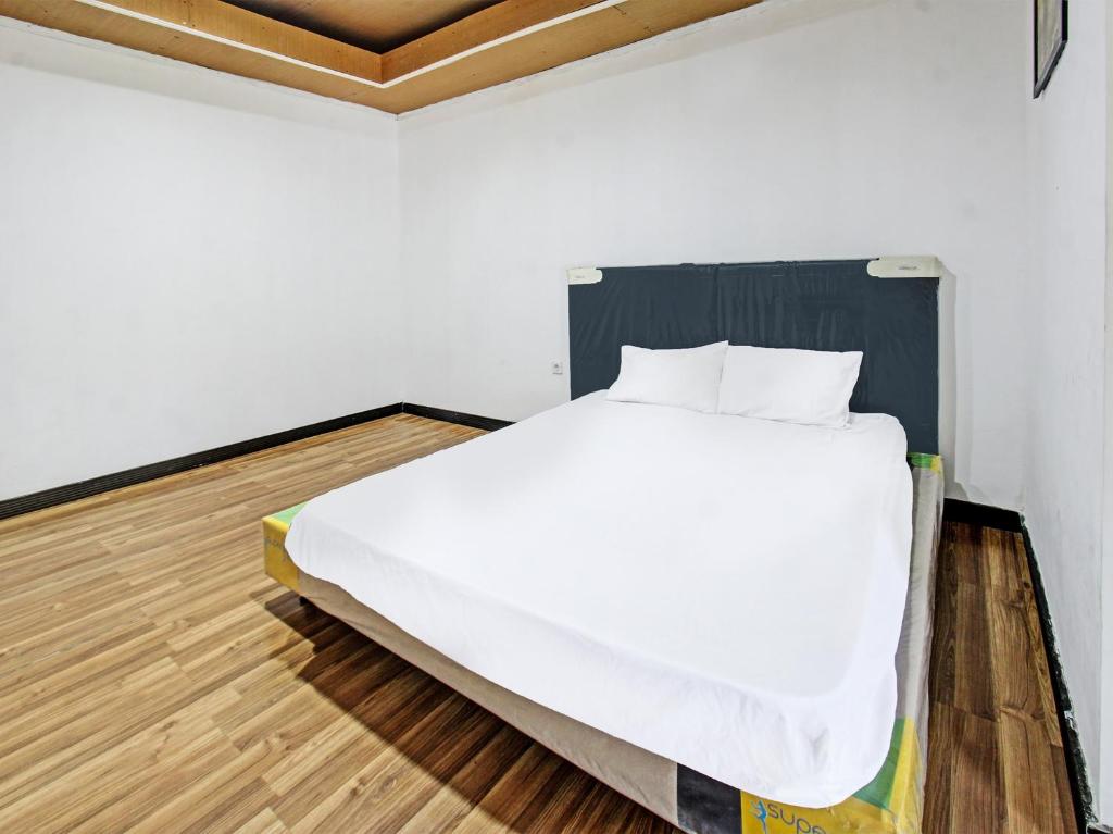 a bedroom with a white bed and a wooden floor at OYO 92090 Panorama Rinjani Lodge in Labuan Lombok