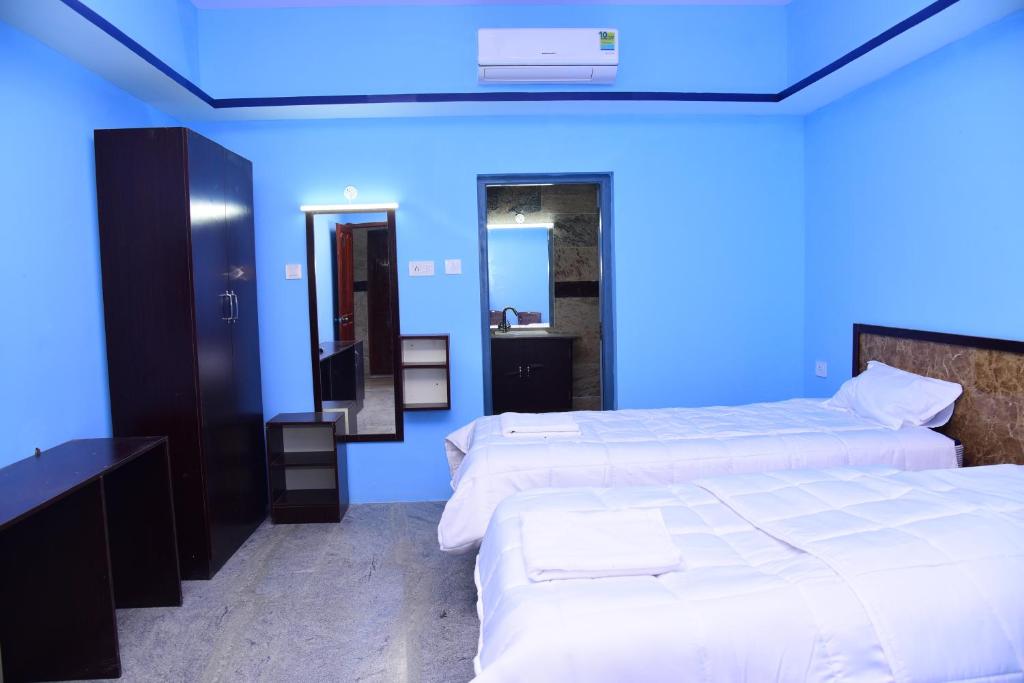 a blue room with two beds and a mirror at Thangam Residency in Kāraikkudi