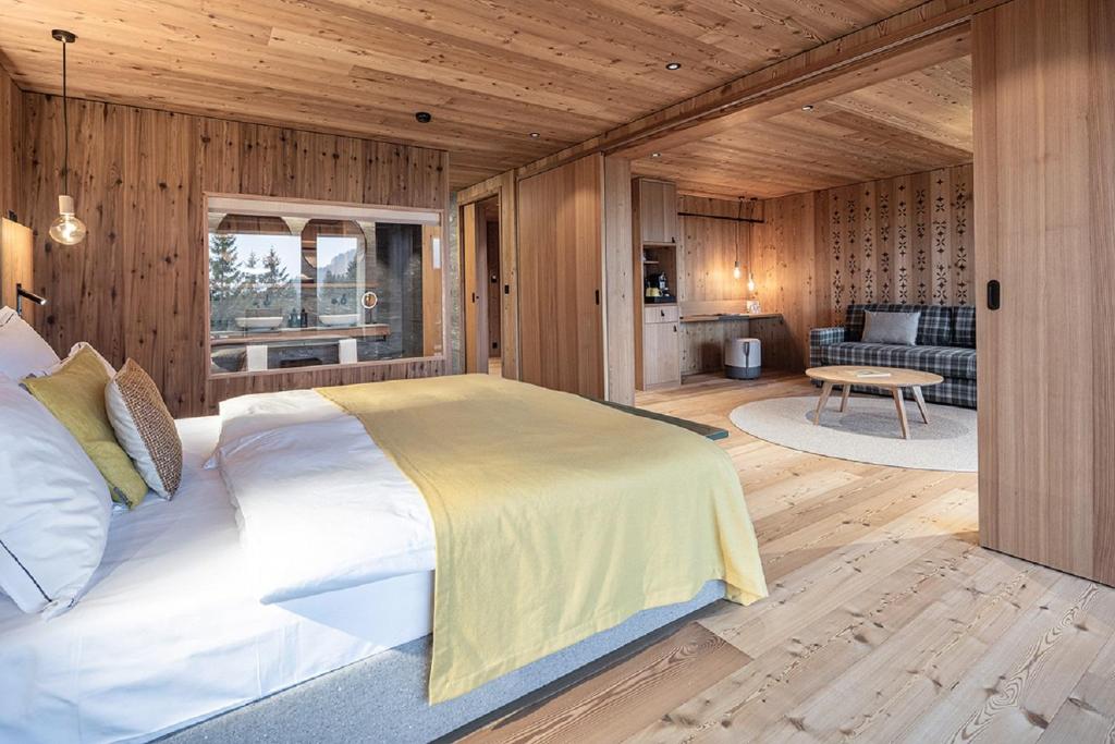 Valbella Resort في لينتسرهايدي: غرفة نوم بسرير كبير في غرفة بجدران خشبية