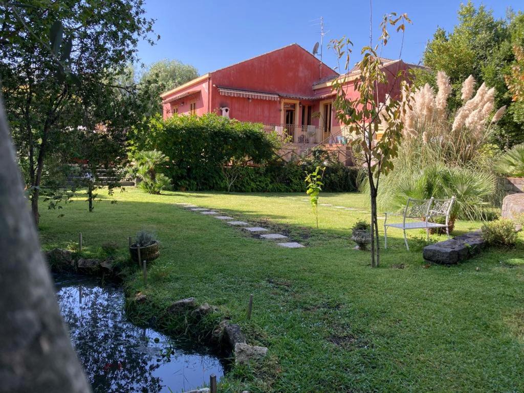 een rood huis met een vijver voor een tuin bij Casa Gino Petrulli Etna, villa con piscina in Zafferana Etnea