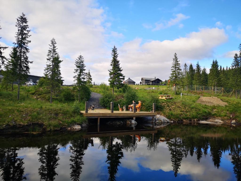 a bridge over a lake with people sitting on it at Blåfjell hundesenter fjellhotell in Mosjøen