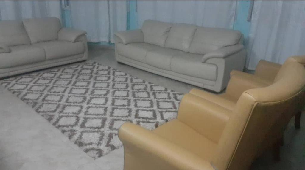 een woonkamer met een bank en 2 stoelen bij Dutchlond Rooms in Freetown