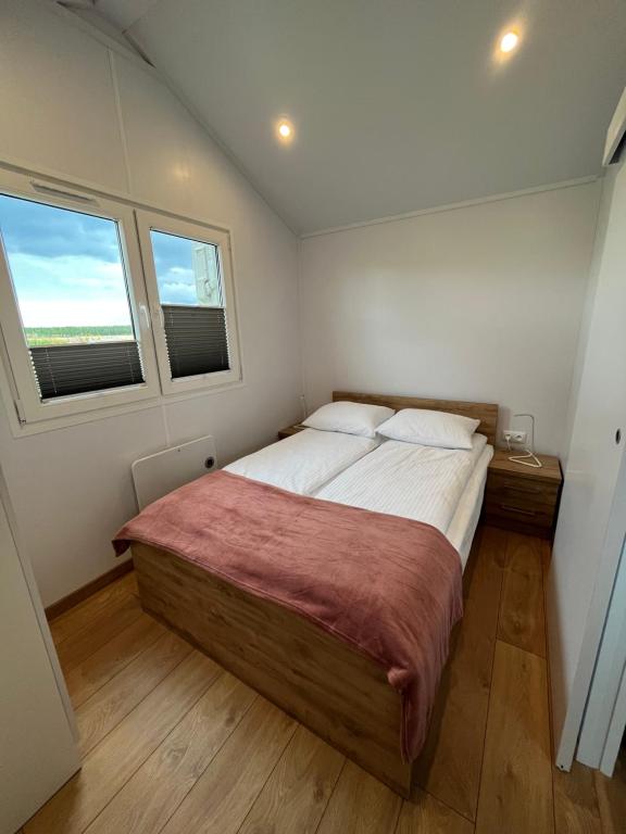 een slaapkamer met een groot bed en 2 ramen bij Słoneczny Pagórek in Giżycko