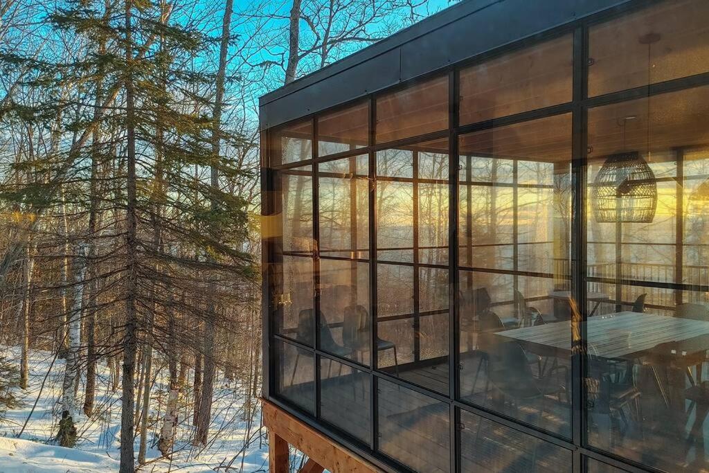 une maison en verre avec vue sur les bois dans l'établissement Le Lo - Fleuve - Forêt - Spa - 10 min du Massif, à Petite-Rivière-Saint-François