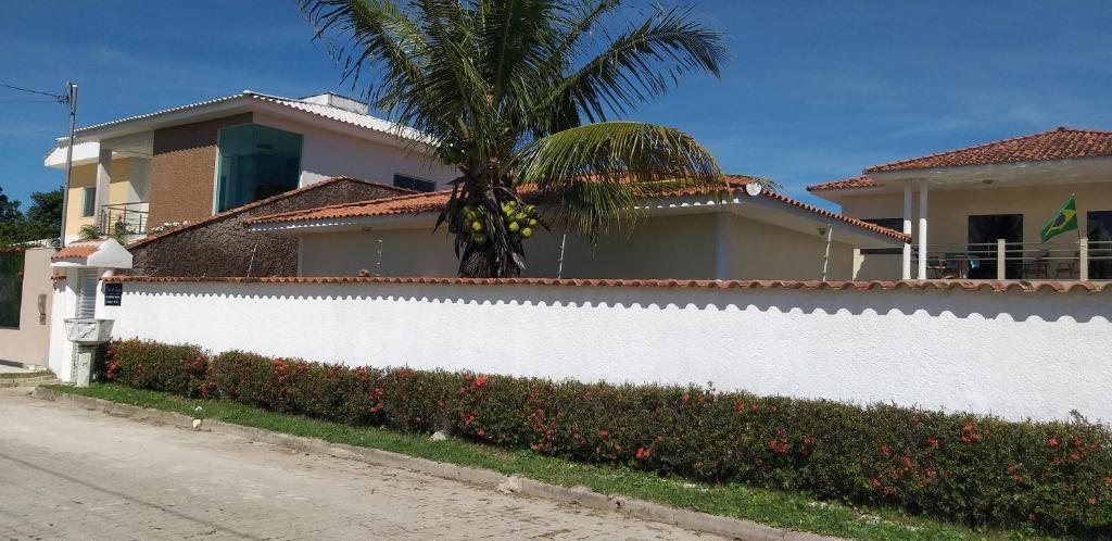 a white fence in front of a house with a palm tree at Na Casa da Anna in Porto Seguro