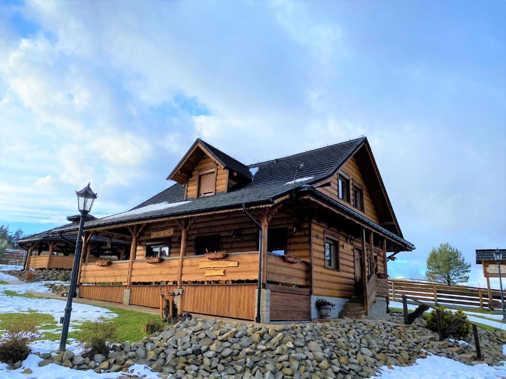 a large wooden cabin with a black roof at Nowica 71 Relax Dom Świerkowy in Nowica