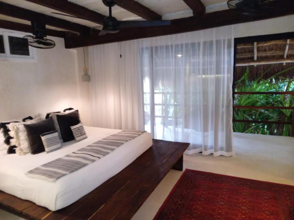 a bedroom with a large bed and a large window at Amor Rooms in Tulum