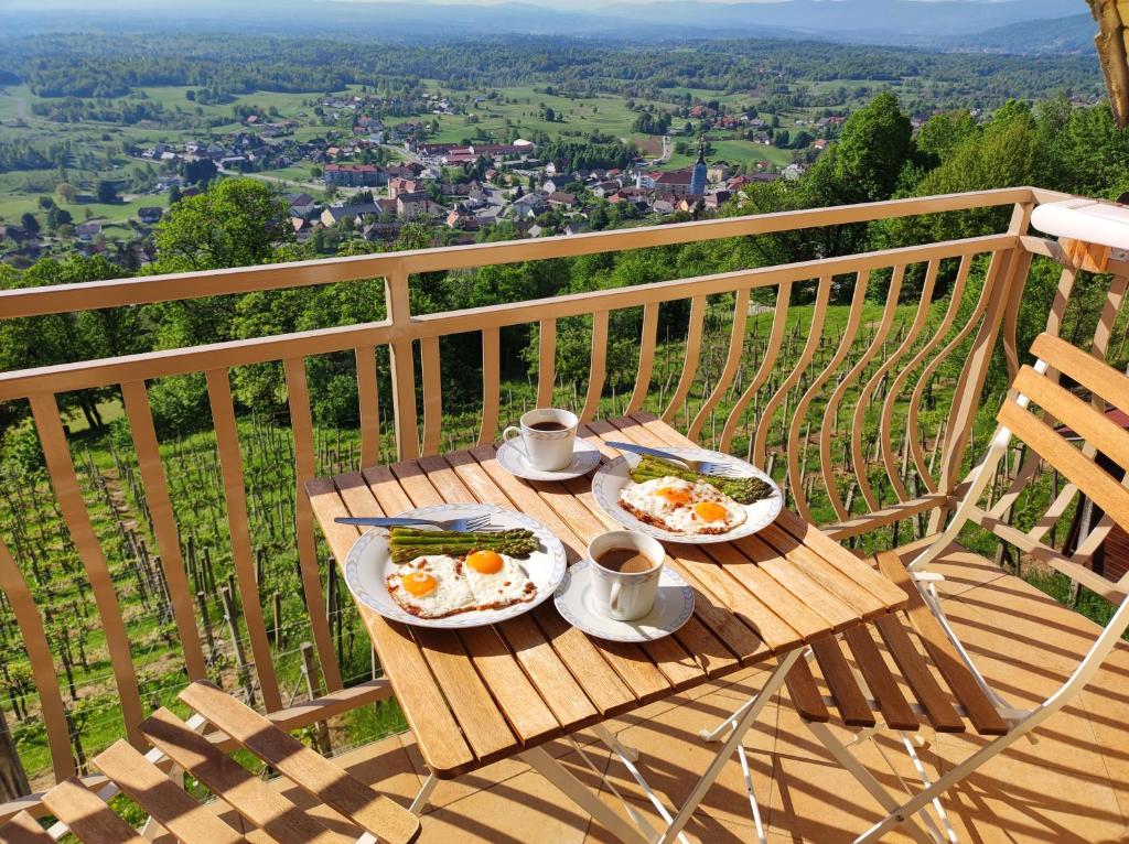 deux assiettes d'œufs sur une table en bois sur un balcon dans l'établissement Zidanica-Vineyard Cottage Jakše, à Semič