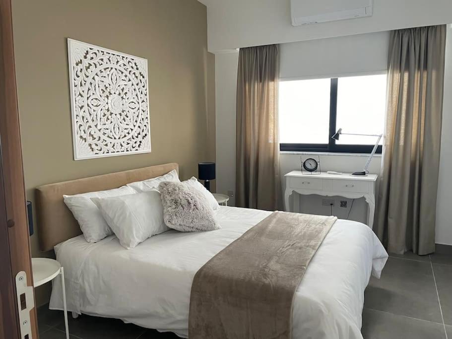 Un dormitorio con una gran cama blanca y una ventana en Luxurious sunlit maisonette with large terrace! en Marsaskala