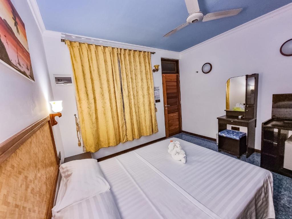 um quarto com uma cama e uma cortina amarela em Suvaasa Inn em Omadhoo