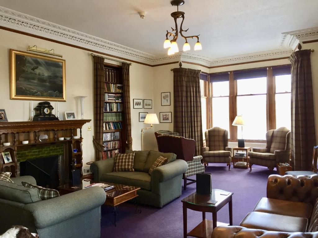 Dalrachney Lodge في كاريبريدج: غرفة معيشة مليئة بالأثاث ومدفأة