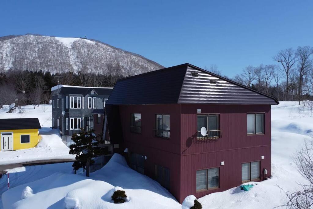 una casa roja con techo negro en la nieve en Rusutsu Washi House, en Rusutsu