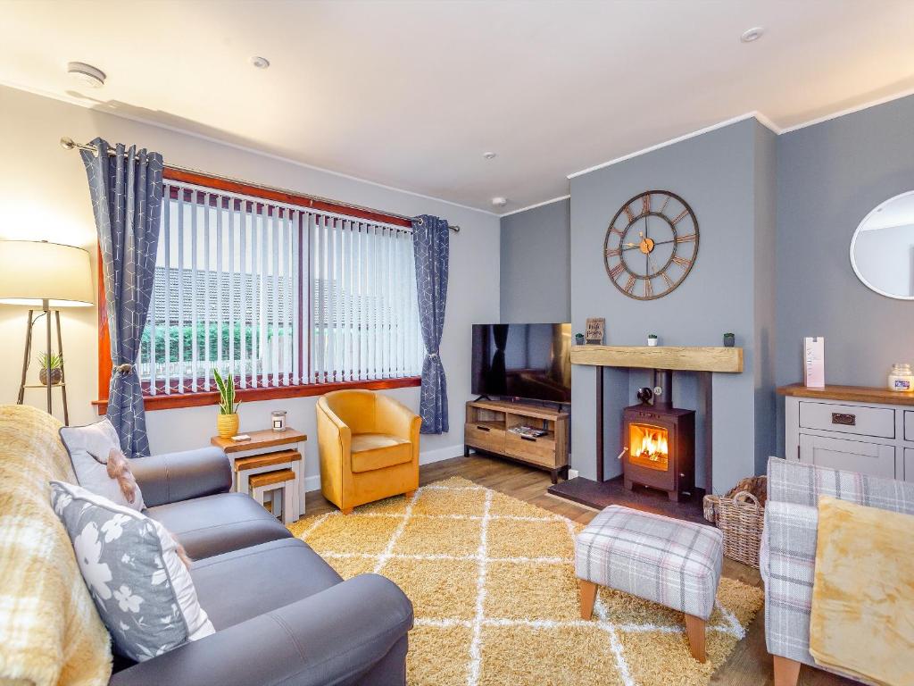 a living room with a couch and a fireplace at Parkhill Cottage in Kildary