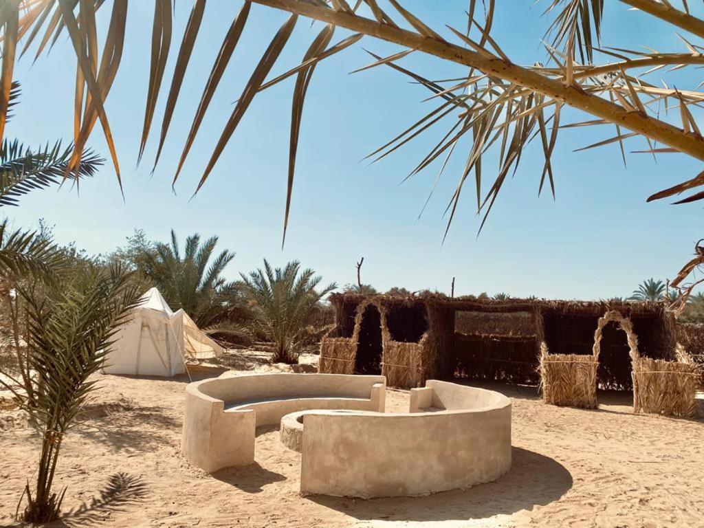 a desert encampment with a tent and two couches in the sand at Siwa Desert Home in ‘Izbat Ţanāţī