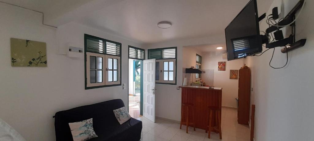 a living room with a couch and a tv and windows at Résidence KAYA, Marie-Galante, Vue Mer in Grand-Bourg