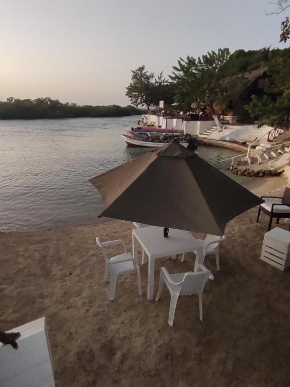 a table and chairs on the beach with an umbrella at PARAISO REAL in Isla Grande