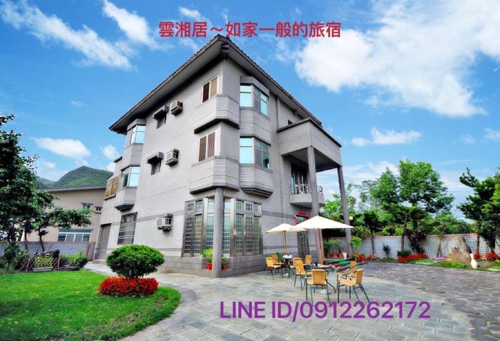 a large apartment building with tables and chairs in front of it at Yun Siang Ju Homestay in Jiaoxi