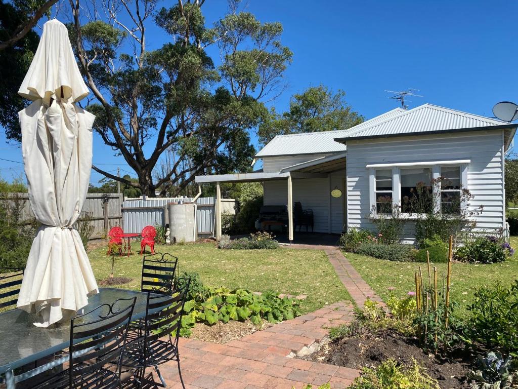 een huis met een tafel en een witte paraplu bij Edwardian Getaway in Wonthaggi