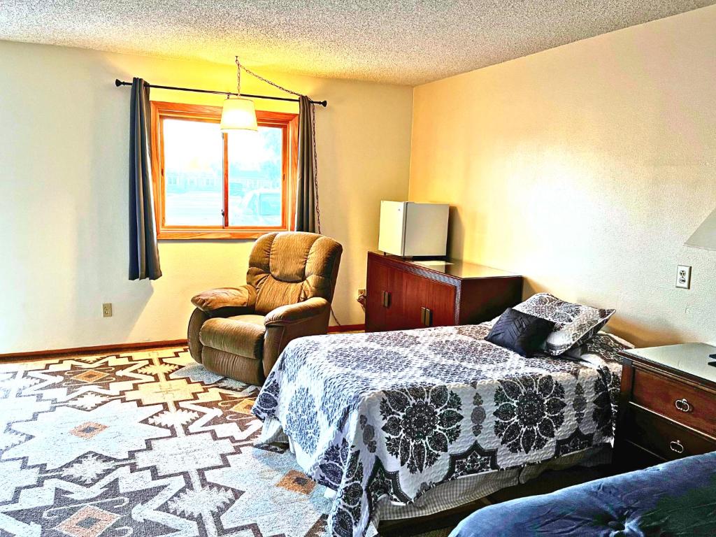 a bedroom with a bed and a chair and a window at Furnas County Lodging in Beaver City