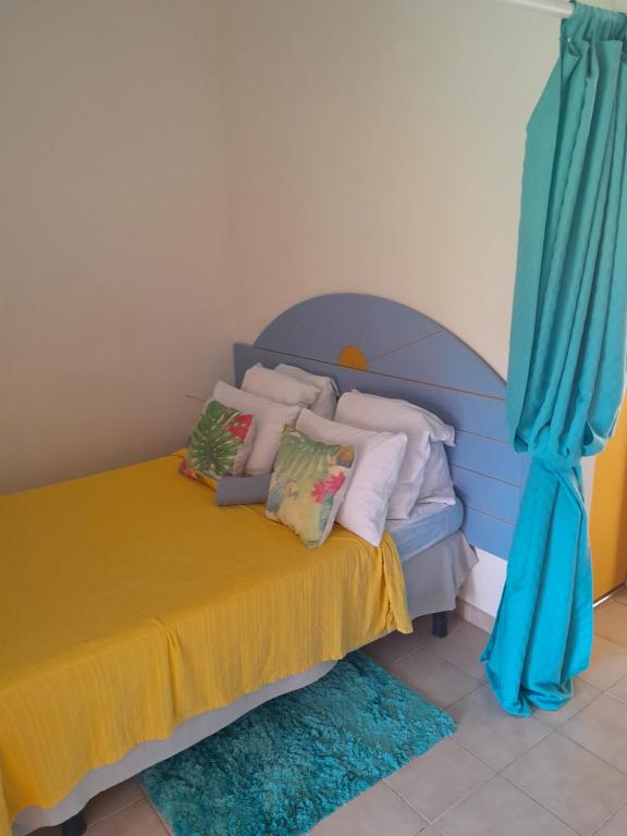 a bedroom with a blue bed with pillows and blue curtains at My Tiny Caritan- Petit coin de paradis- Bungalow de vacances- jardin, plage, piscine attenante in Sainte-Anne