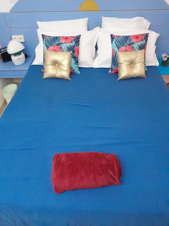un letto blu con un cuscino rosso sopra di My Tiny Caritan- Petit coin de paradis- Bungalow de vacances- jardin, plage, piscine attenante a Sainte-Anne