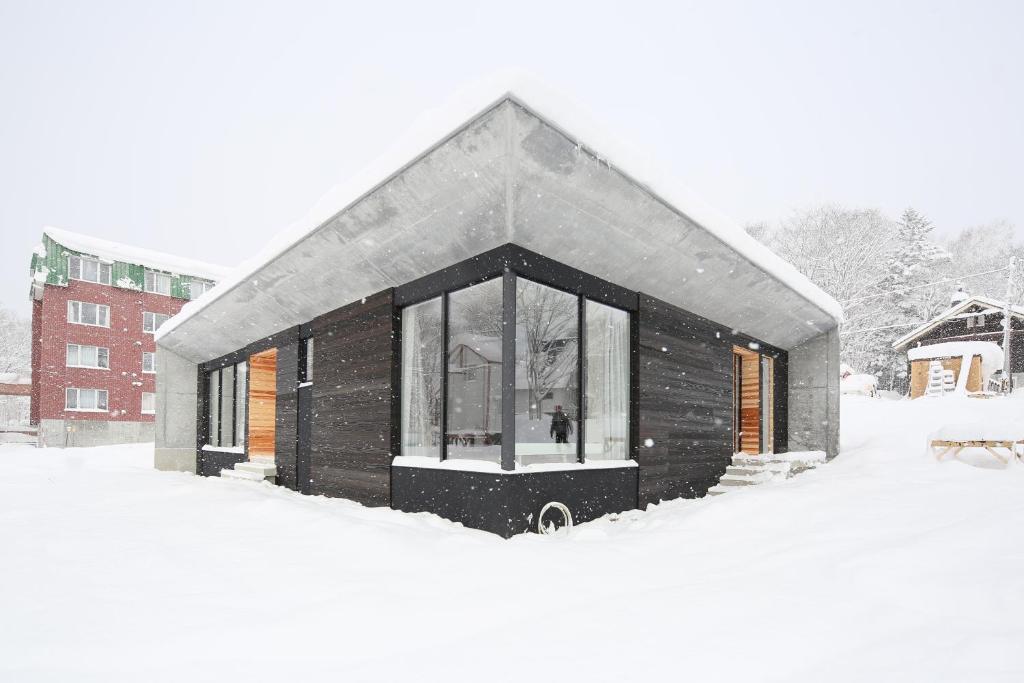 um pequeno edifício coberto de neve num quintal em Niseko Bisha 美舎 Onsen Villas em Niseko