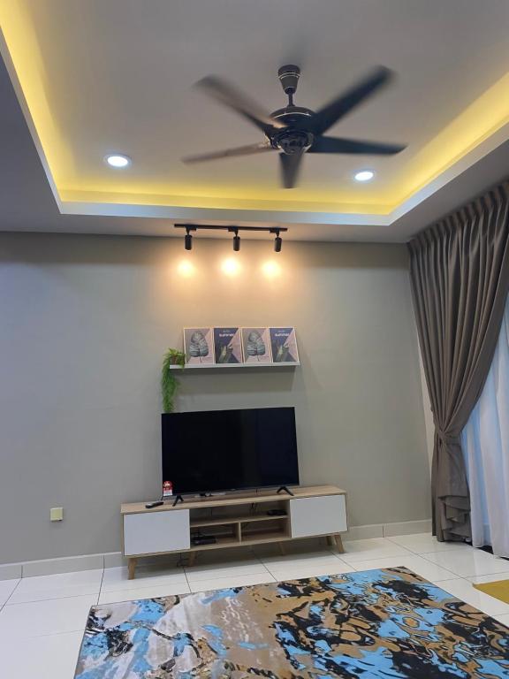 uma sala de estar com uma televisão e uma ventoinha de tecto em Ana Homestay em Batu Pahat