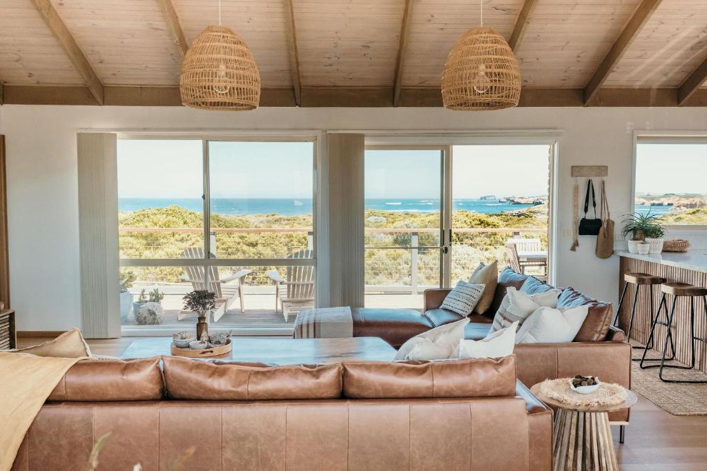 a living room with a couch and a table at Sunsets on Martyrs Luxury Coastal Beach House Peterborough in Peterborough