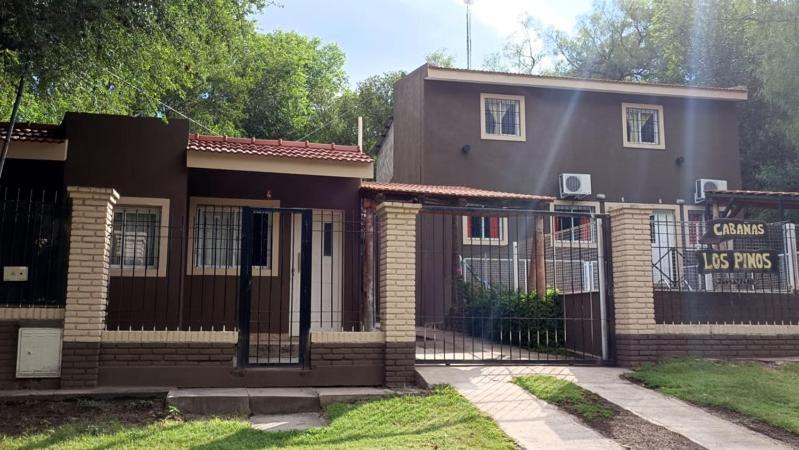 a house with a fence and a sign on it at Cabañas Los Pinos in Potrero de los Funes