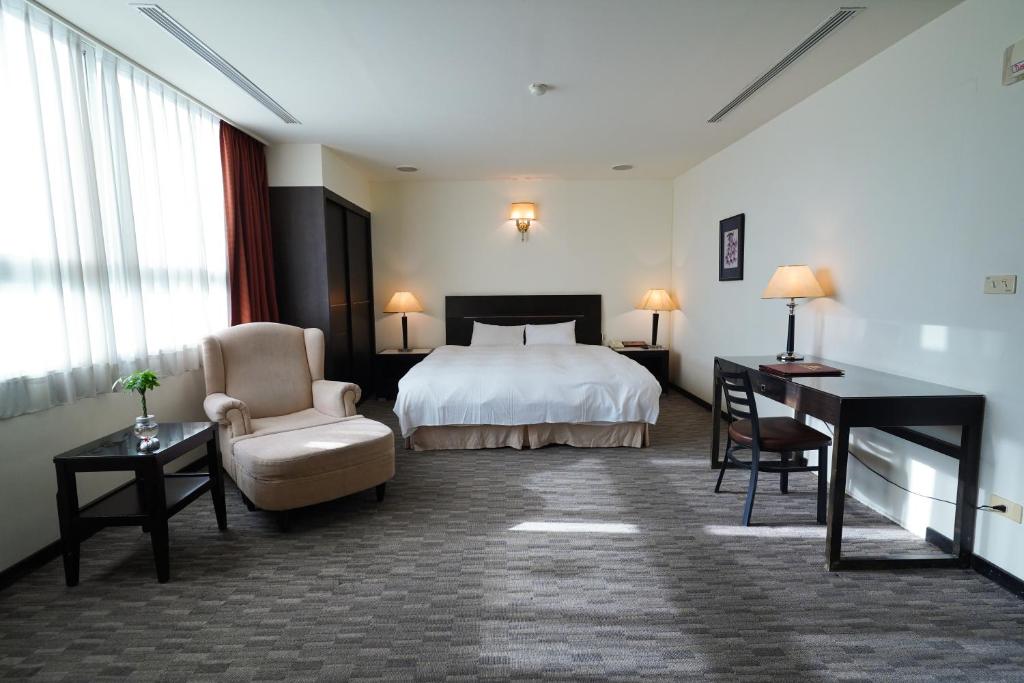 a hotel room with a bed and a desk and a chair at Herkang Hotel in Taichung