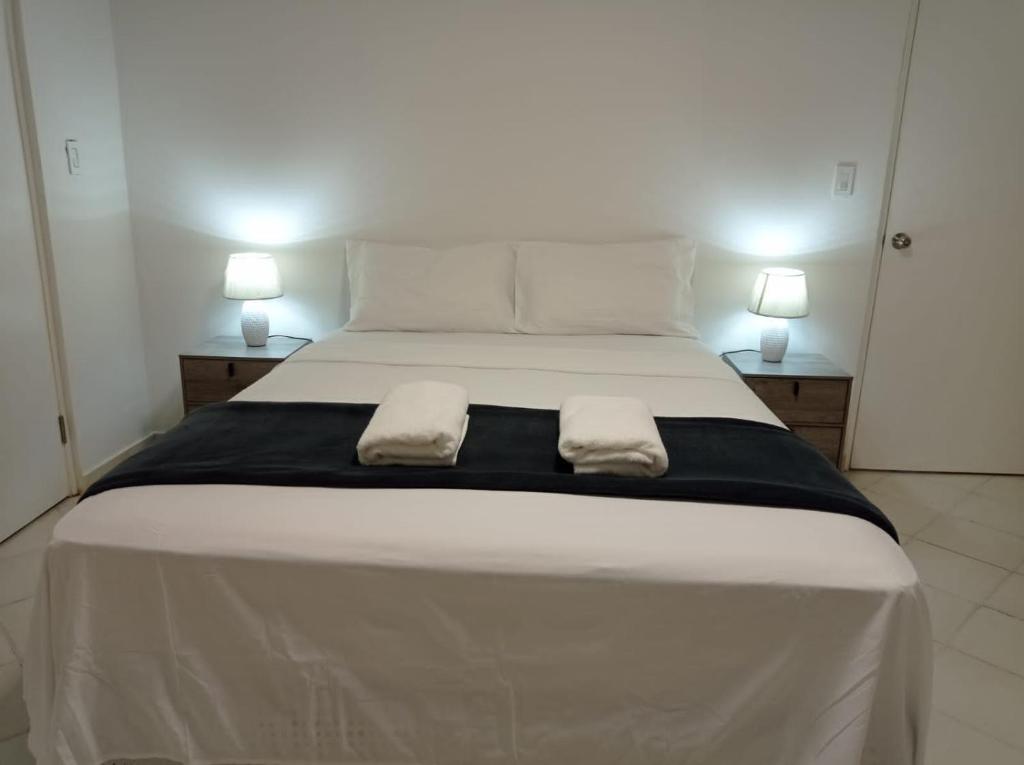 een groot wit bed met 2 handdoeken erop bij Doña Nancy in Panama-Stad