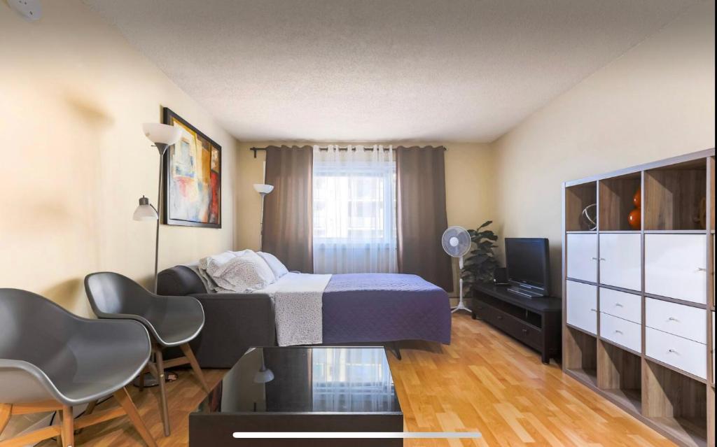 - une chambre avec un lit, un bureau et une télévision dans l'établissement Downtown River Valley Bachelor Suite Condo, NON Smoking, 12 inches Queen Bed, Beautiful Minimalist, very convenient every where, à Edmonton