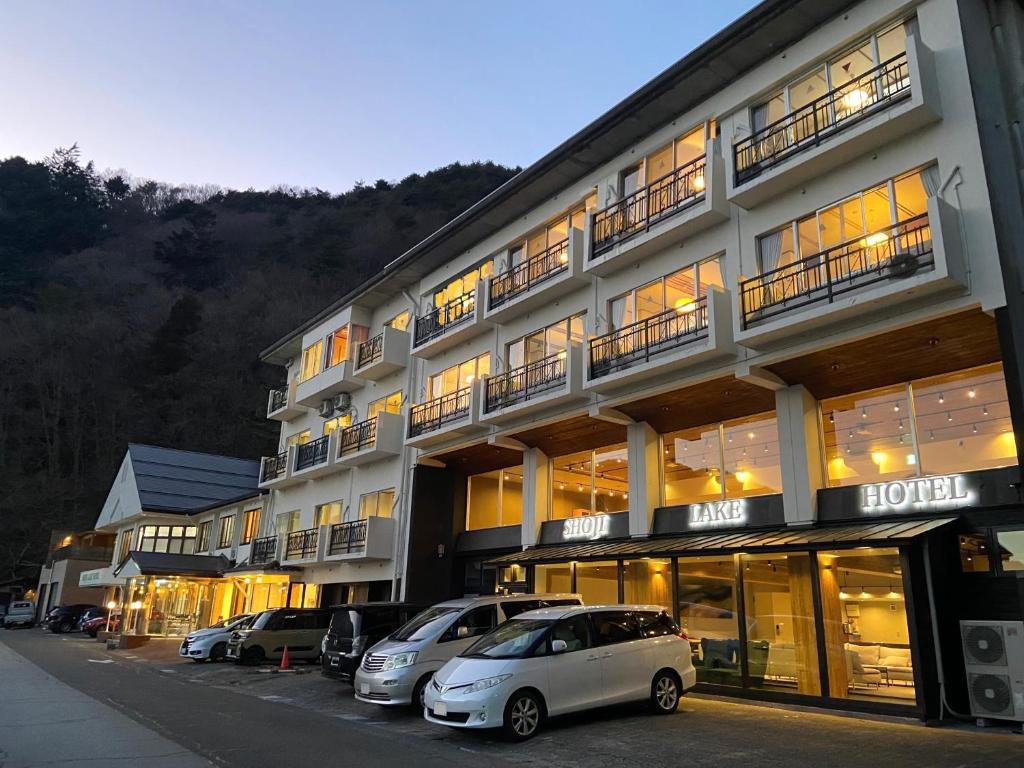 um grande edifício com carros estacionados em frente em Shoji Lake Hotel em Fujikawaguchiko