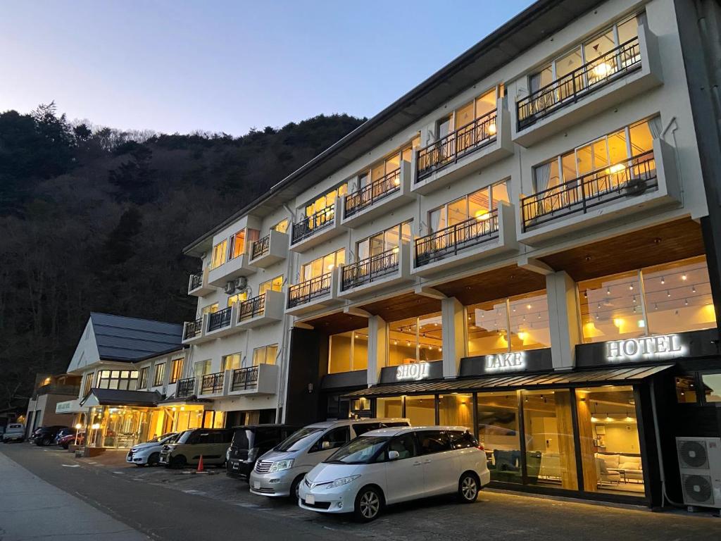 a large building with cars parked in front of it at Shoji Lake Hotel in Fujikawaguchiko